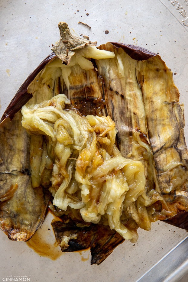 a roasted eggplant being scraped out with a fork to make Middle Eastern eggplant dip