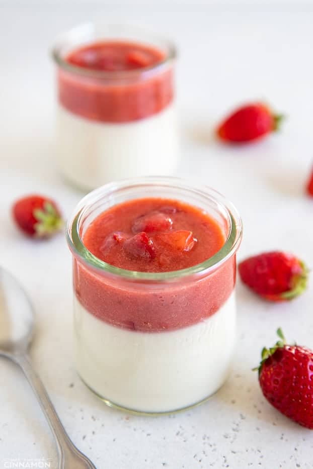 side view of a jar of coconut milk panna cotta topped with fresh strawberry puree