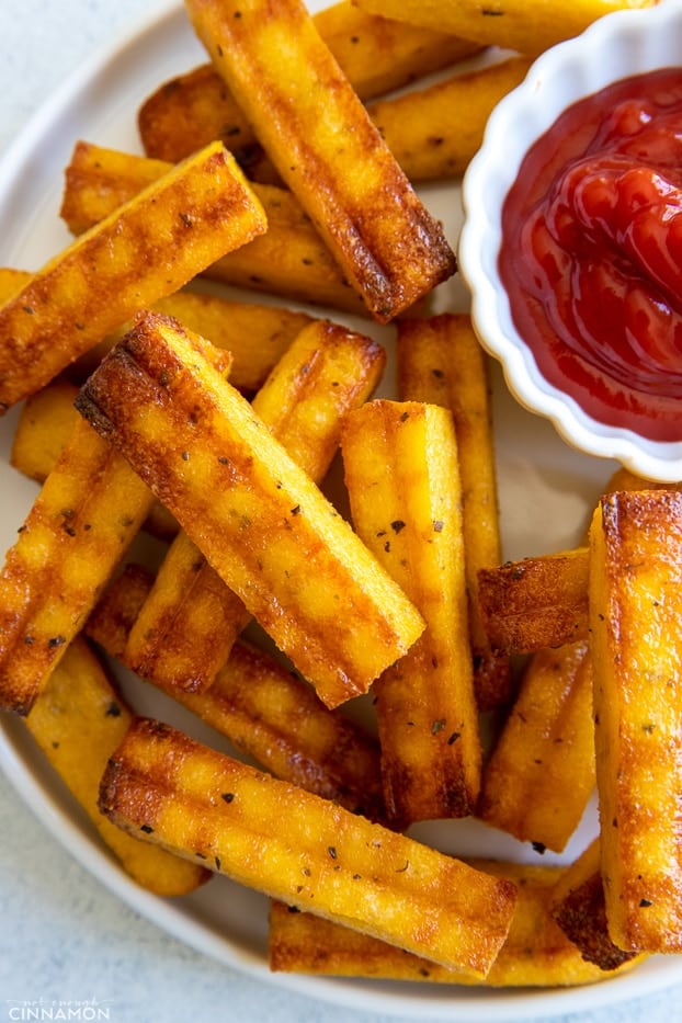 overhead shot of a serving of healthy baked polenta fries served with a small dish with ketchup 