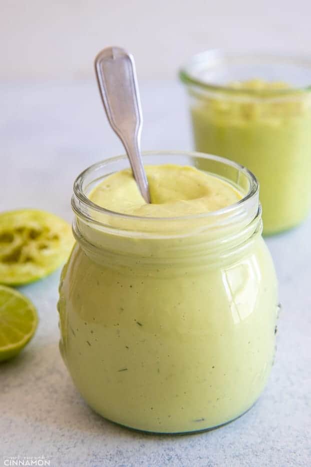 a spoon being dipped in a small jar with with vegan healthy avocado ranch dip