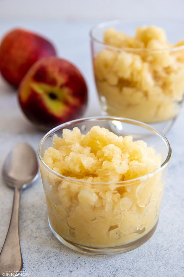 side view of glass filled with homemade peach granita with a spoon on the side 