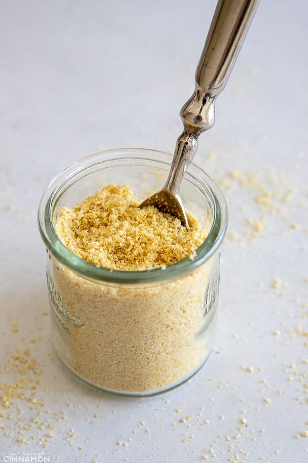 a spoon in a small jar with homemade vegan parmesan cheese made from cashews 