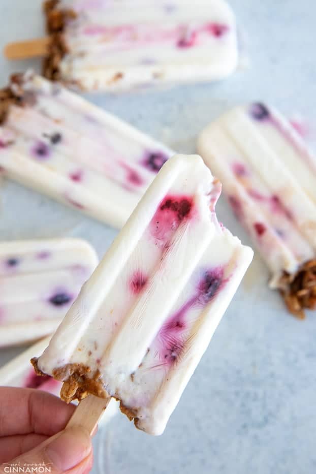 a hand holding a healthy popsicle with yogurt, berries and honey 