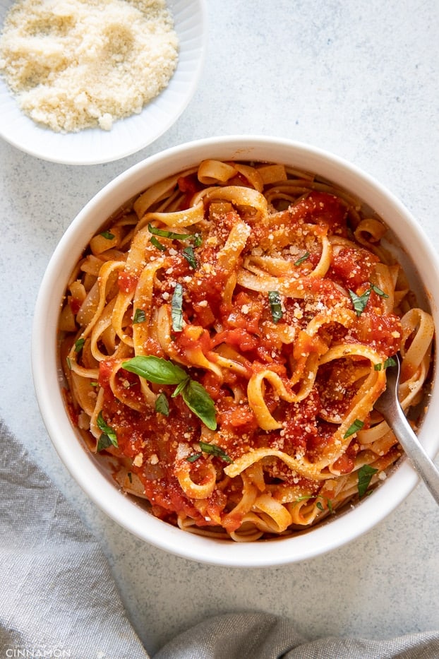 overhead shot of a bowl of pasta with homemade marinara sacue and grated parmesan cheese