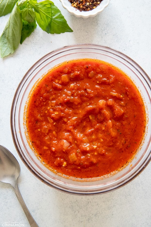 overhead shot of a small bowl of homemade marinara sauce with a spoon on the side