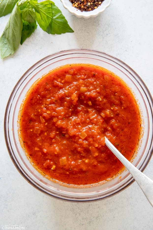 overhead shot of a small bowl with marinara sauce with a silver spoon