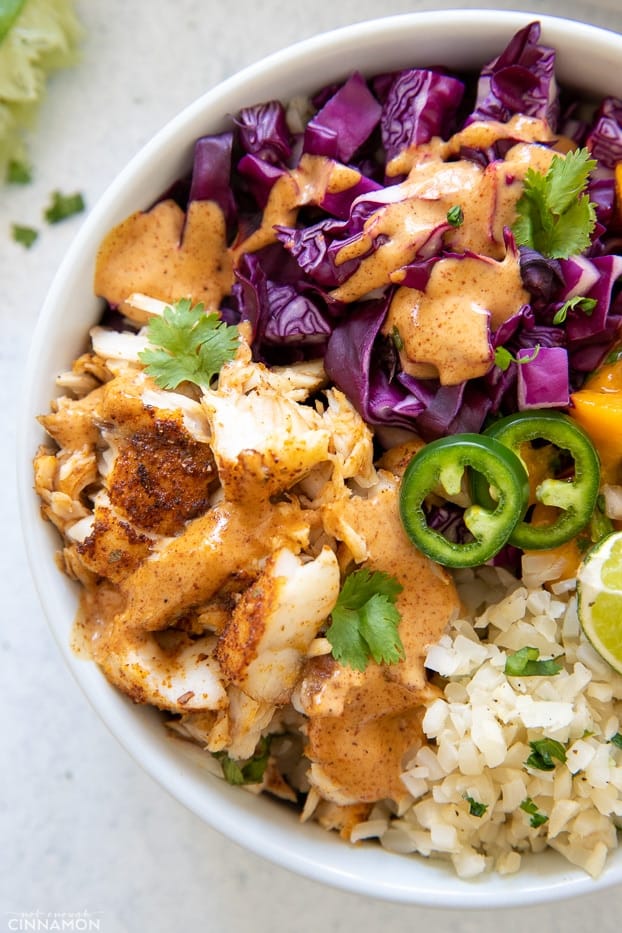 overhead closeup of a paleo fish taco bowl with red cabbage slaw, baked barramundi and jalapeños on cauliflower rice