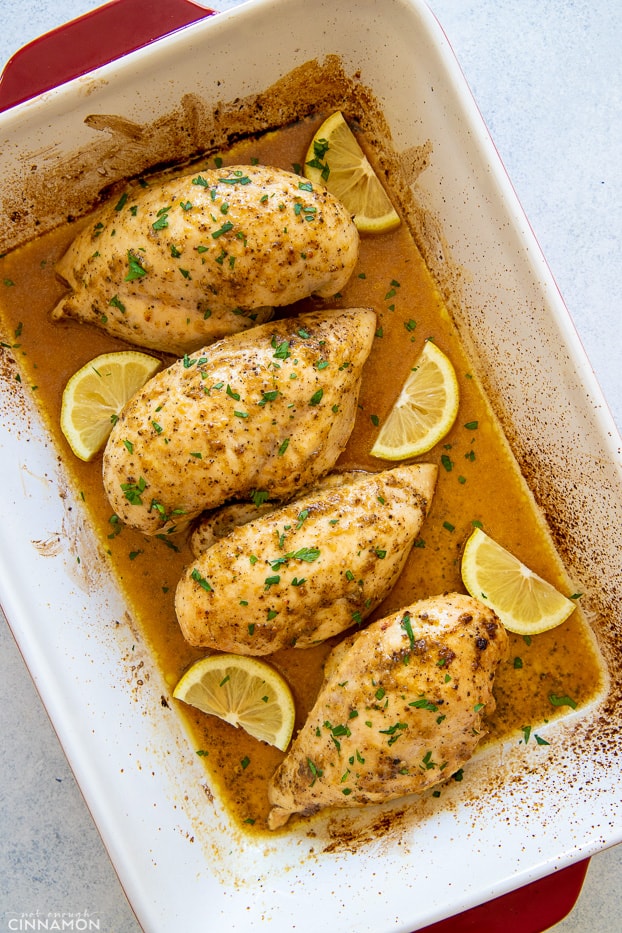 overhead shot of baked lemon pepper chicken breast in a white casserole 