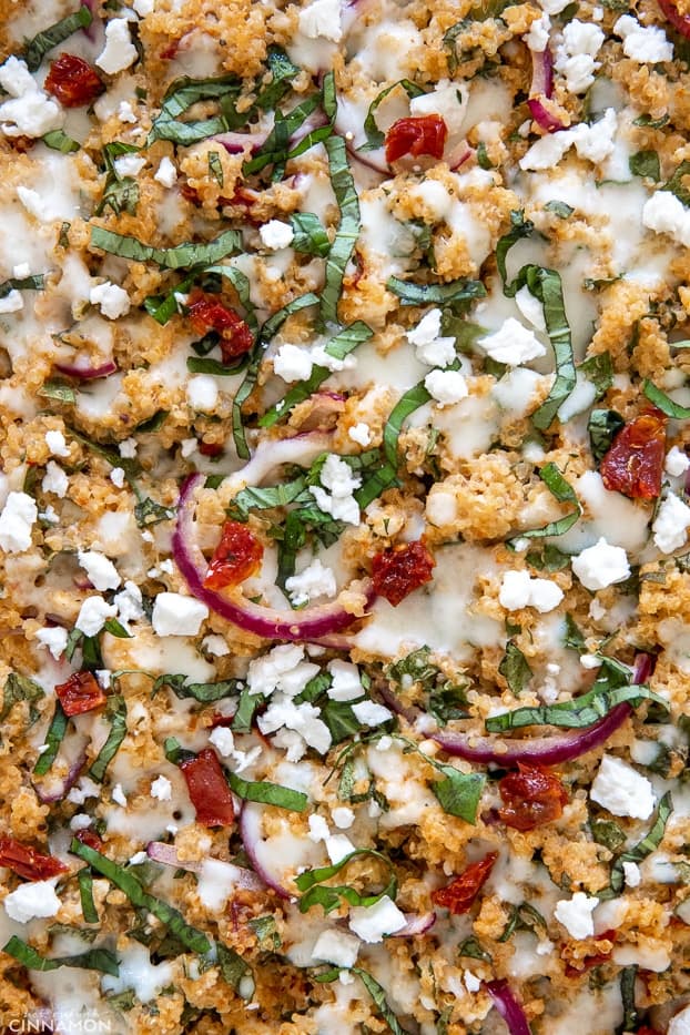 overhead shot of healthy quinoa casserole sprinkled with feta, tomatoes and basil