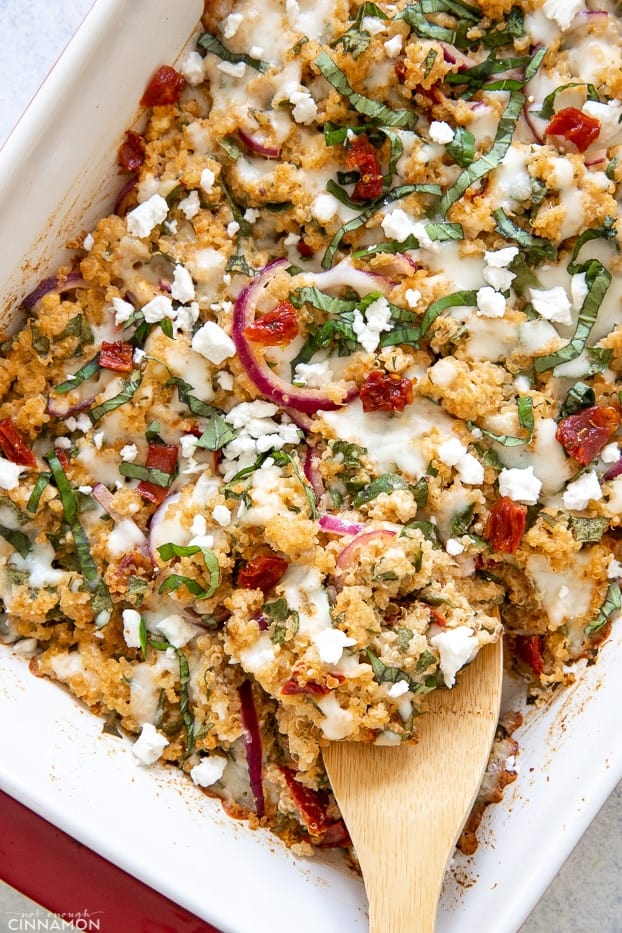 a wooden spoon being inserted into a healthy feta tomato quinoa bake 