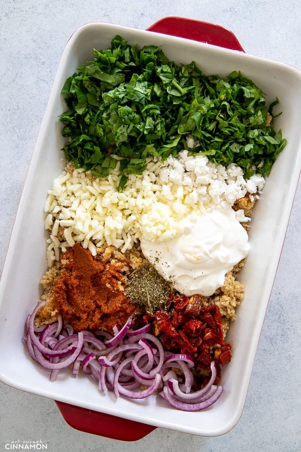 ingredients for quinoa casserole in a white and red casserole dish