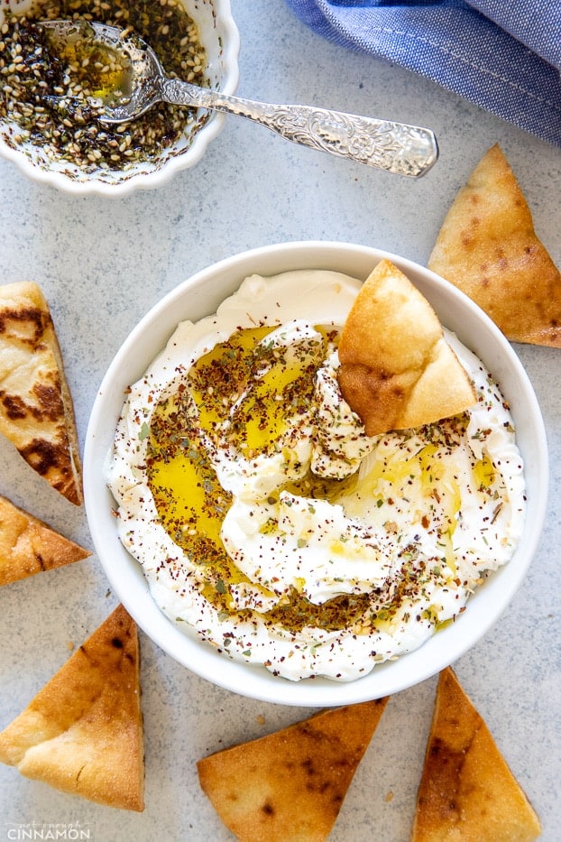 overhead shot of a white bowl filled with labneh with pita chips on the side