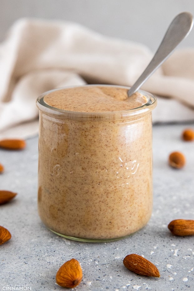close-up of a jar of almond butter with a sliver spoon sticking from it 