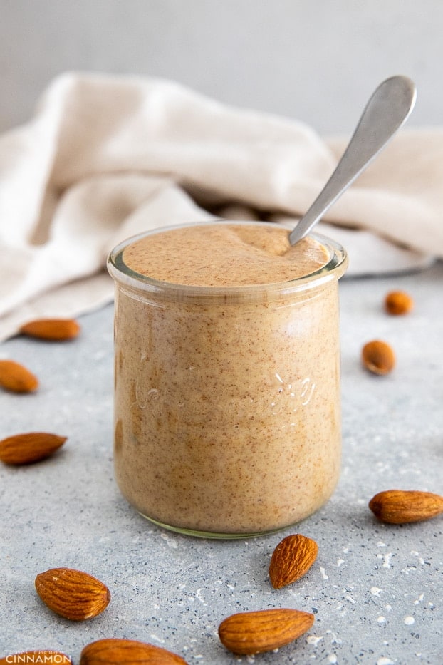 a small jar of homemade almond butter with a spoon sticking in