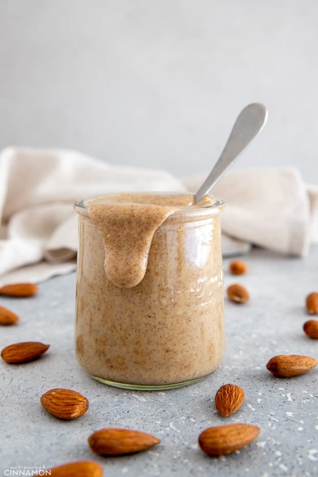 homemade almond butter in a small glass jar with some butter running down the side