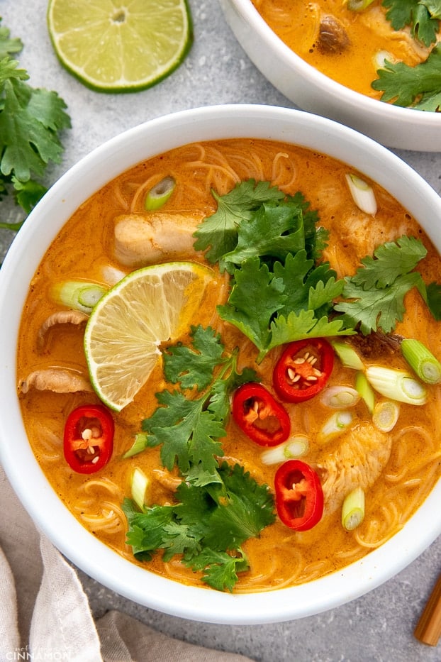 overhead shot of a bowl of Asian Thai Curry Noodle Soup decorated with lime cilantro and chile