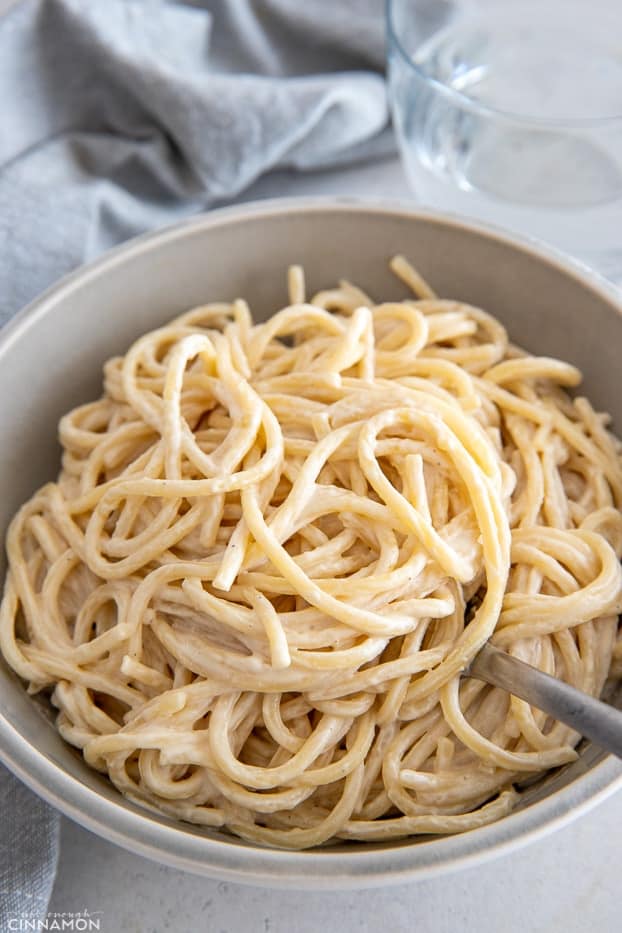 a bowl of creamy vegan lemon tahini pasta with a fork 