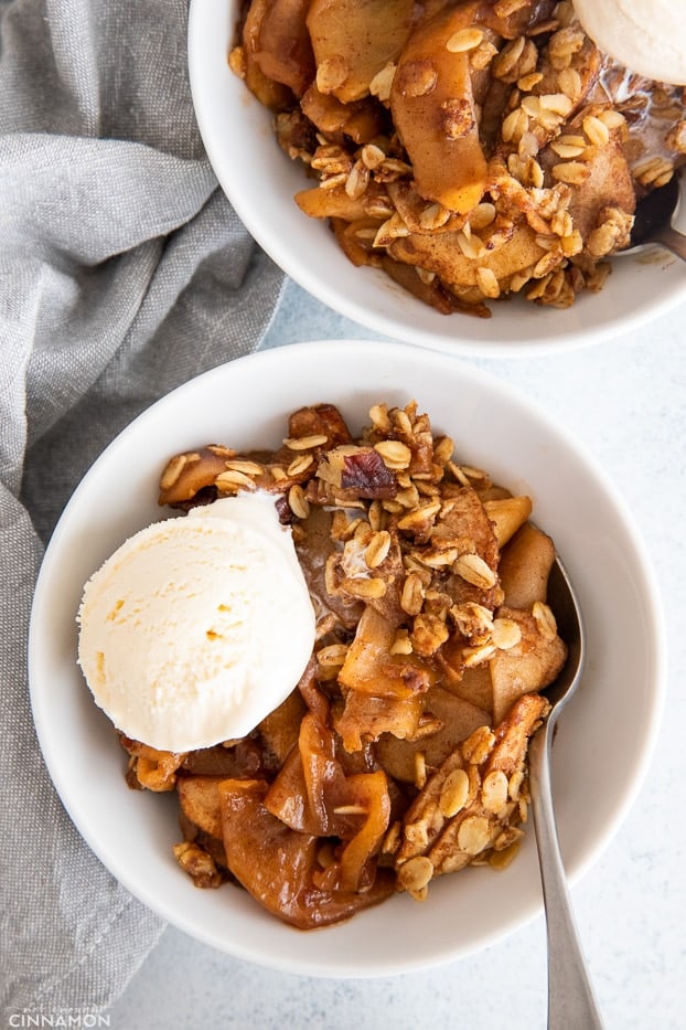 overhead shot of two bowls with healthy apple crisp served with vanilla ice cream