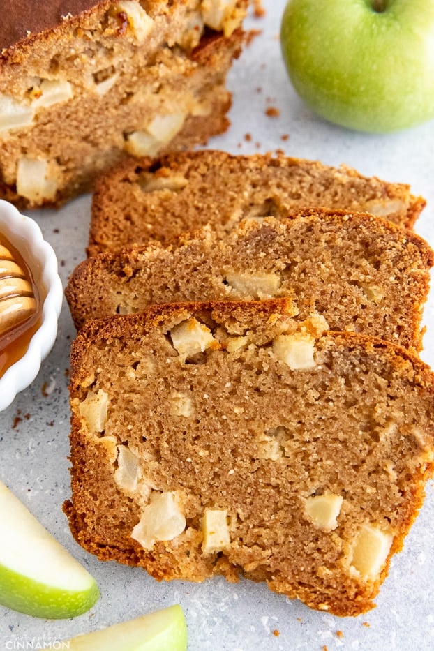 sliced loaf of Paleo Honey Apple Bread with honey and apple slices on the side