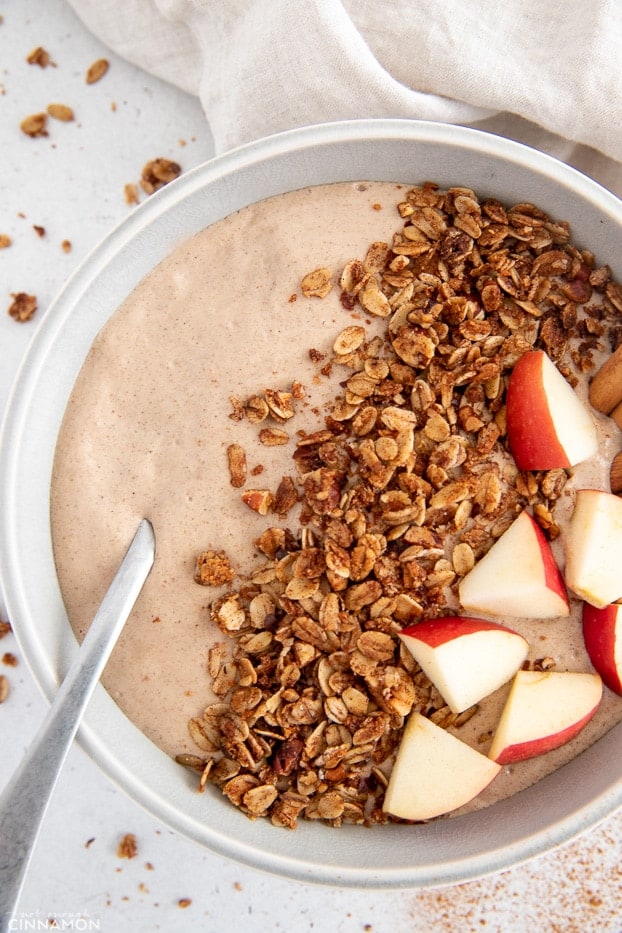 overhead shot of a apple pie smoothie bowl topped with fruit and granola