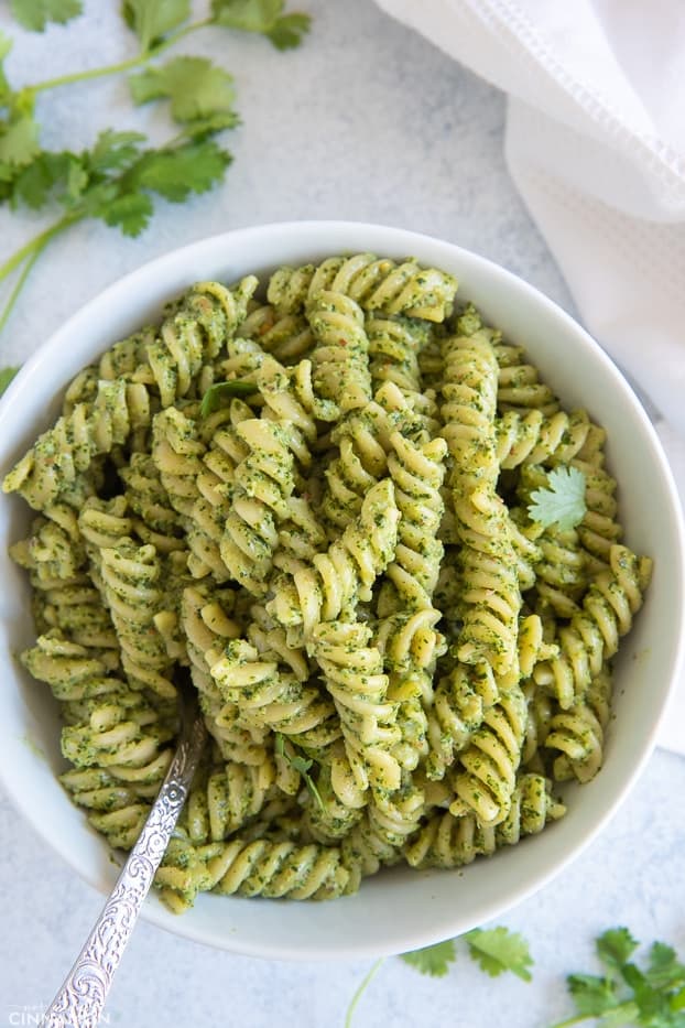 overhead shot of a bowl of creamy cilantro pasta with a spoon 