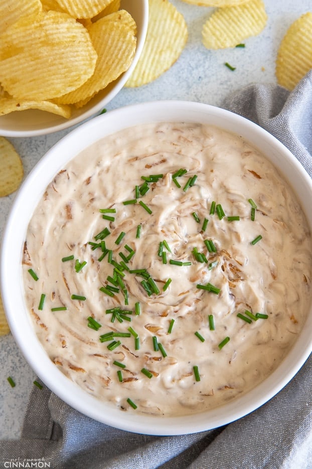 overhead shot of a white bowl with healthy French Onion Dip with a side of chips 