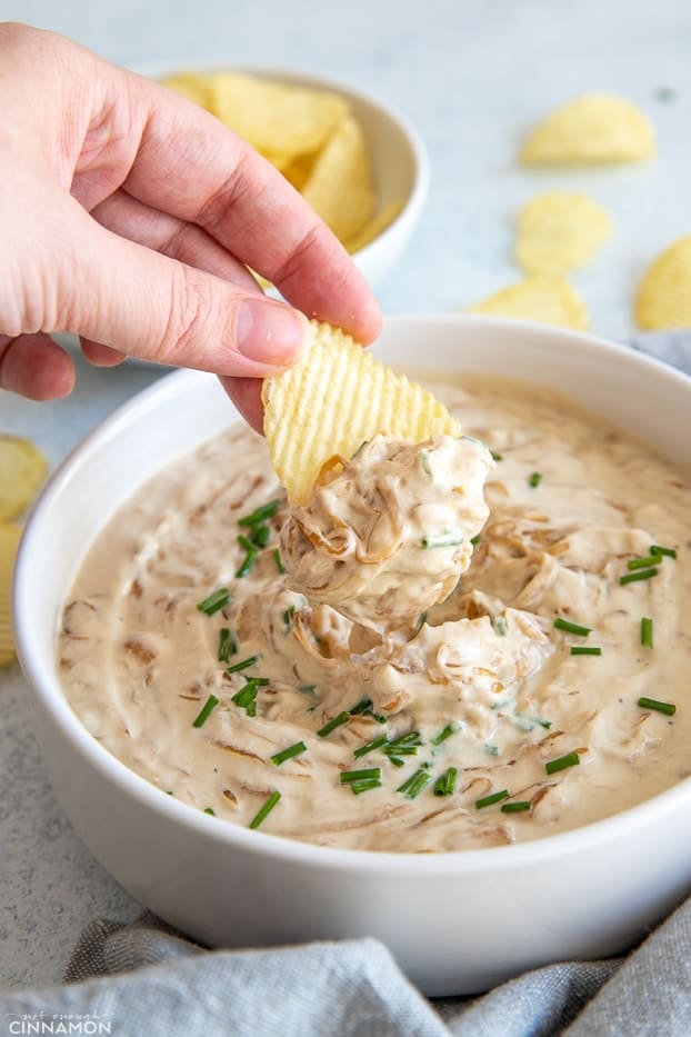 a potato chip being dipped into healthy French Onion Dip 