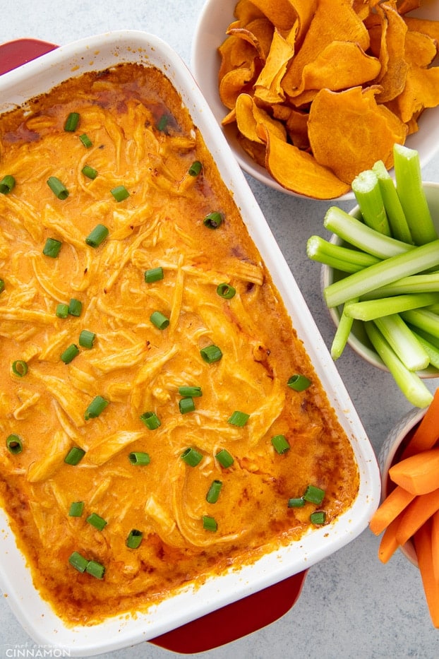 baked paleo buffalo chicken dip in a white casserole dish with dippers on the side 