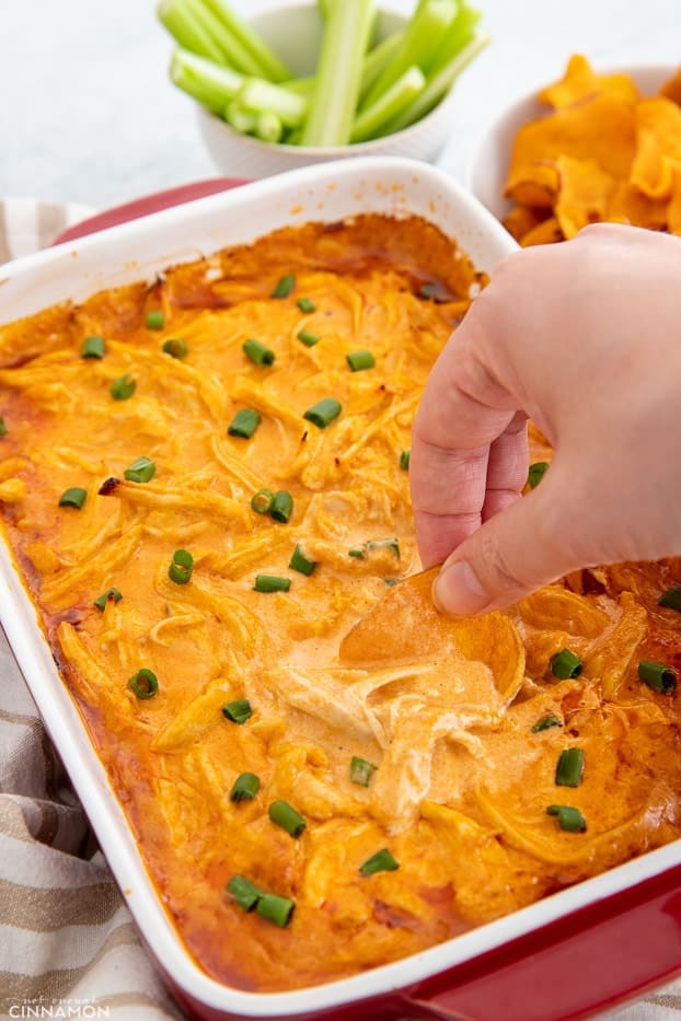 a sweet potato chip being dipped into healthy buffalo chicken dip 