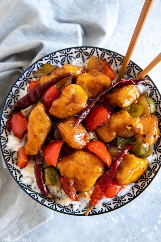 a bowl with Chinese Szechuan Chicken stir fry on rice with chopsticks 