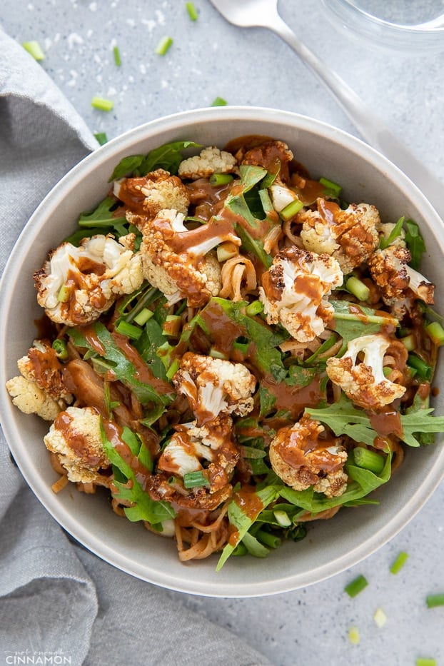 overhead shot of a rice noodle bowl with roasted cauliflower and arugula 