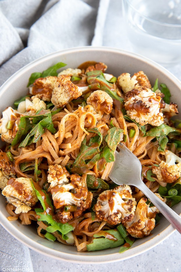 a fork twirling rice noodles tossed in Thai almond butter sauce
