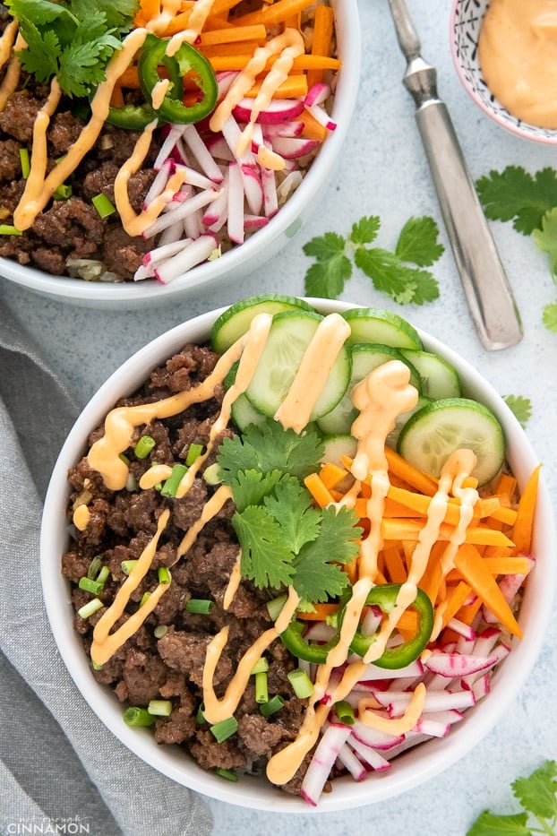 overhead shot of two banh mi rice bowls drizzled with sriracha mayo