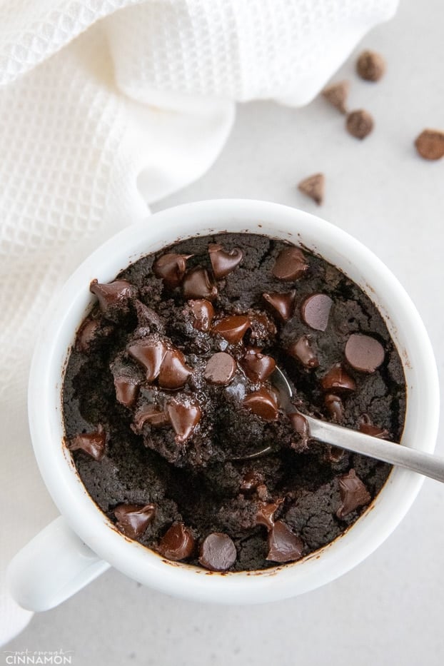 a spoon being dipped into a vegan chocolate mug cake 