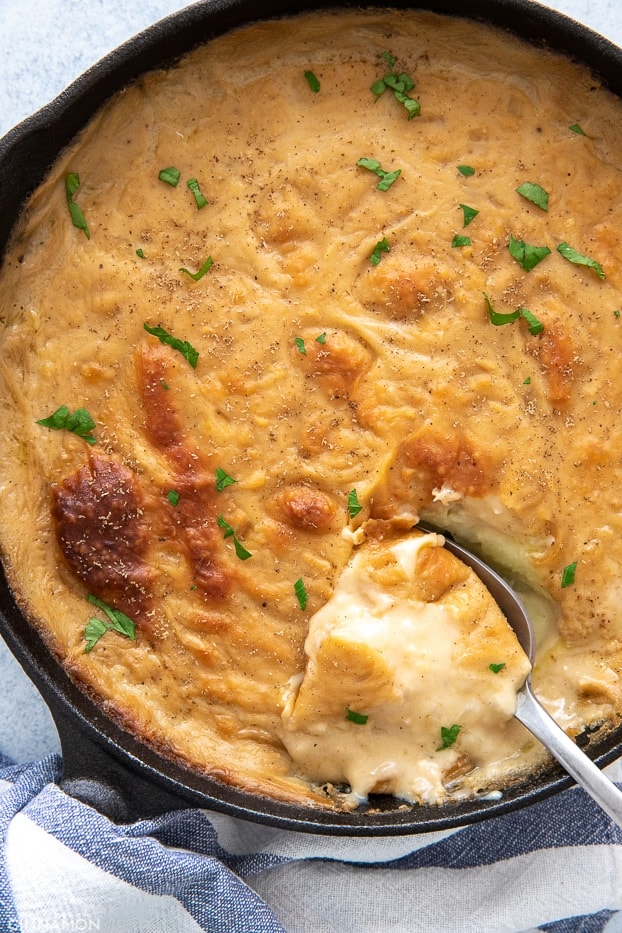 a spoon digging into a skillet with dairyfree scalloped potatoes