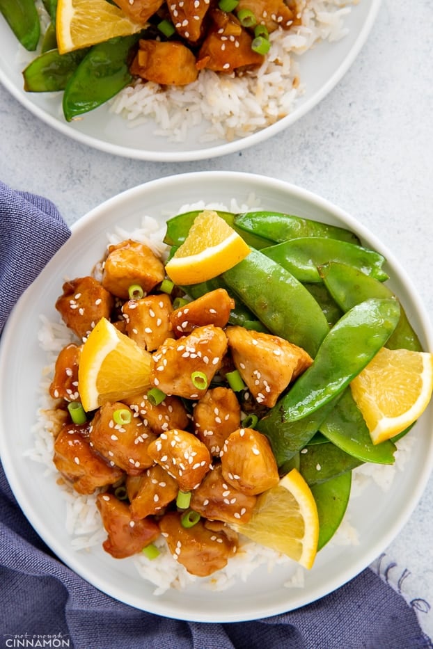 overhead shot of one skillet Chinese style orange chicken served with snow peas and rice