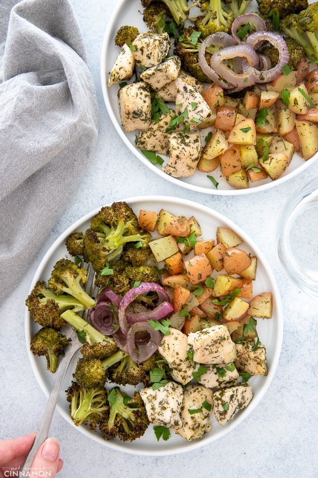 overhead shot of two plates of sheet pan ranch chicken served with baked veggies