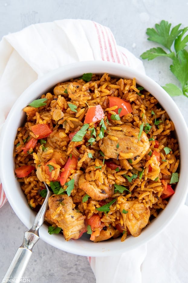 overhead shot of West African Jollof chicken and rice in a white bowl with a spoon