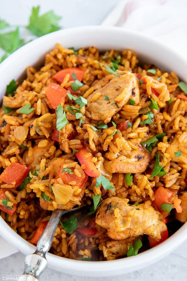 close up of a bowl of West African healthy Jollof rice with chicken sprinkled with cilantro 