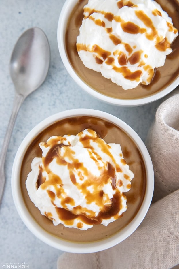 overhead shot of two small bowls of vegan salted caramel pudding topped with coconut cream