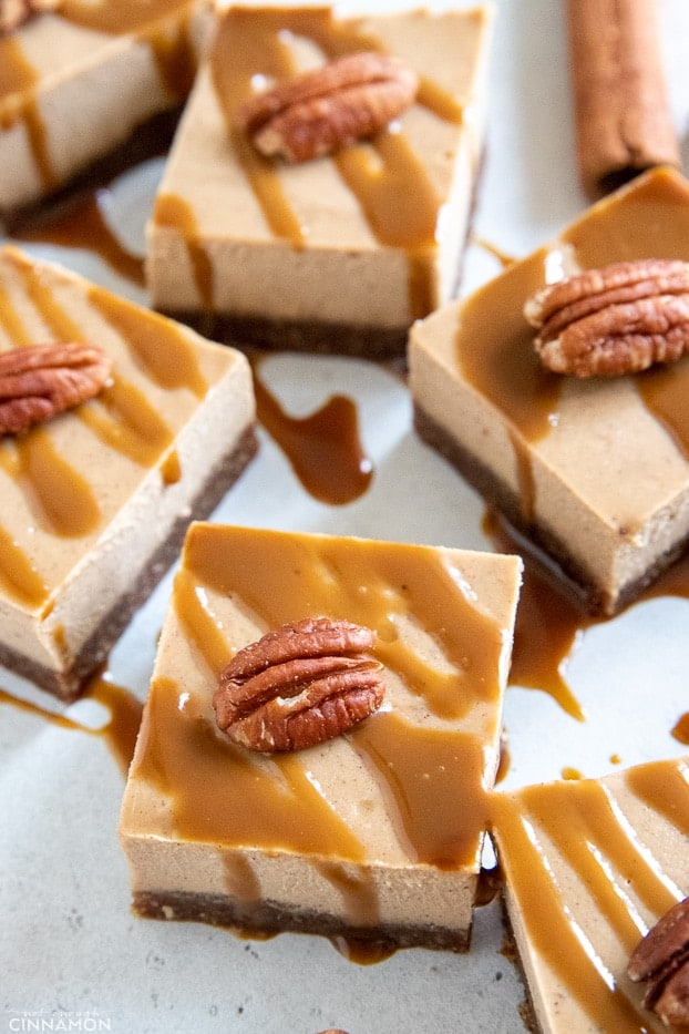 squared of vegan chai spiced cheesecake bars decorated with vegan caramel and pecans