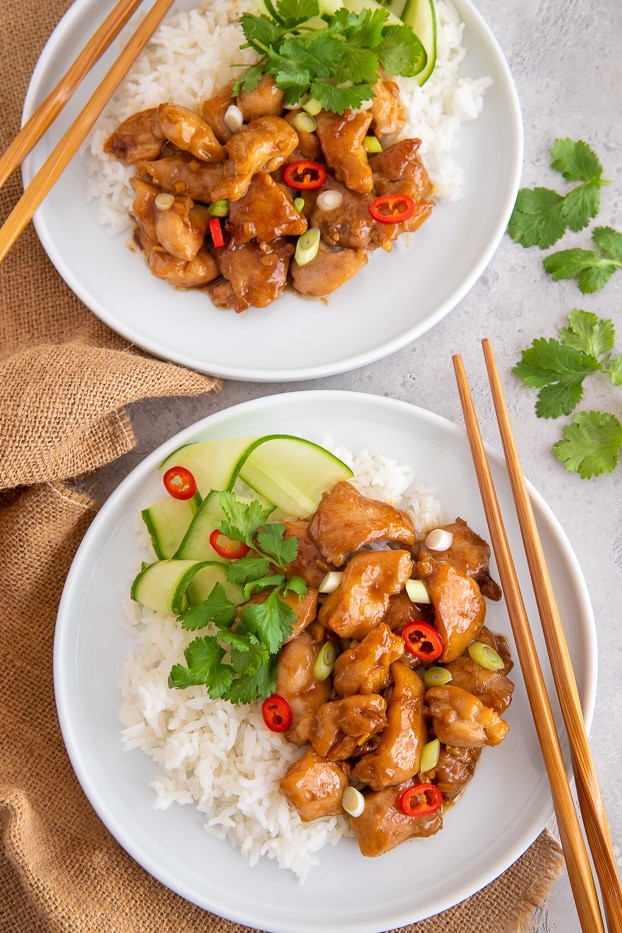 two servings of coconut caramel chicken served with rice and cucumber salad 