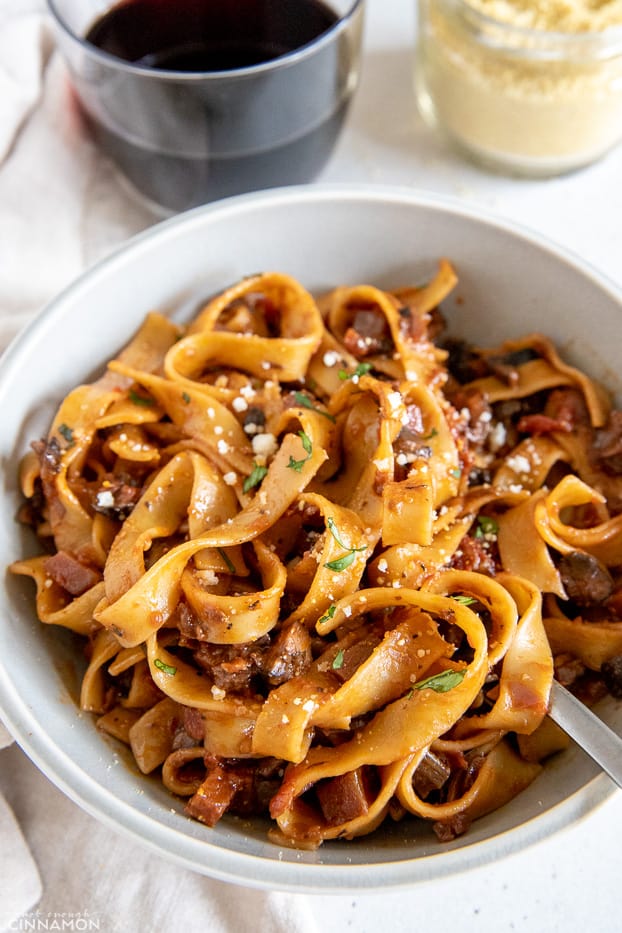 vegan mushroom bolognese pasta with soy sauce and vegan parmesan in the background