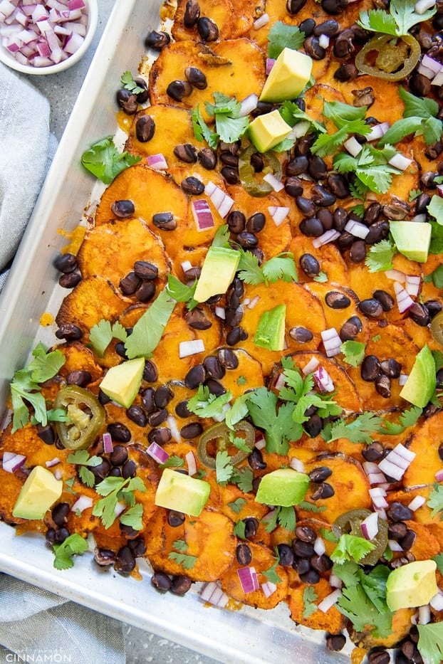 overhead shot of healthy sheet pan sweet potato nachos topped with avocado and cilantro 