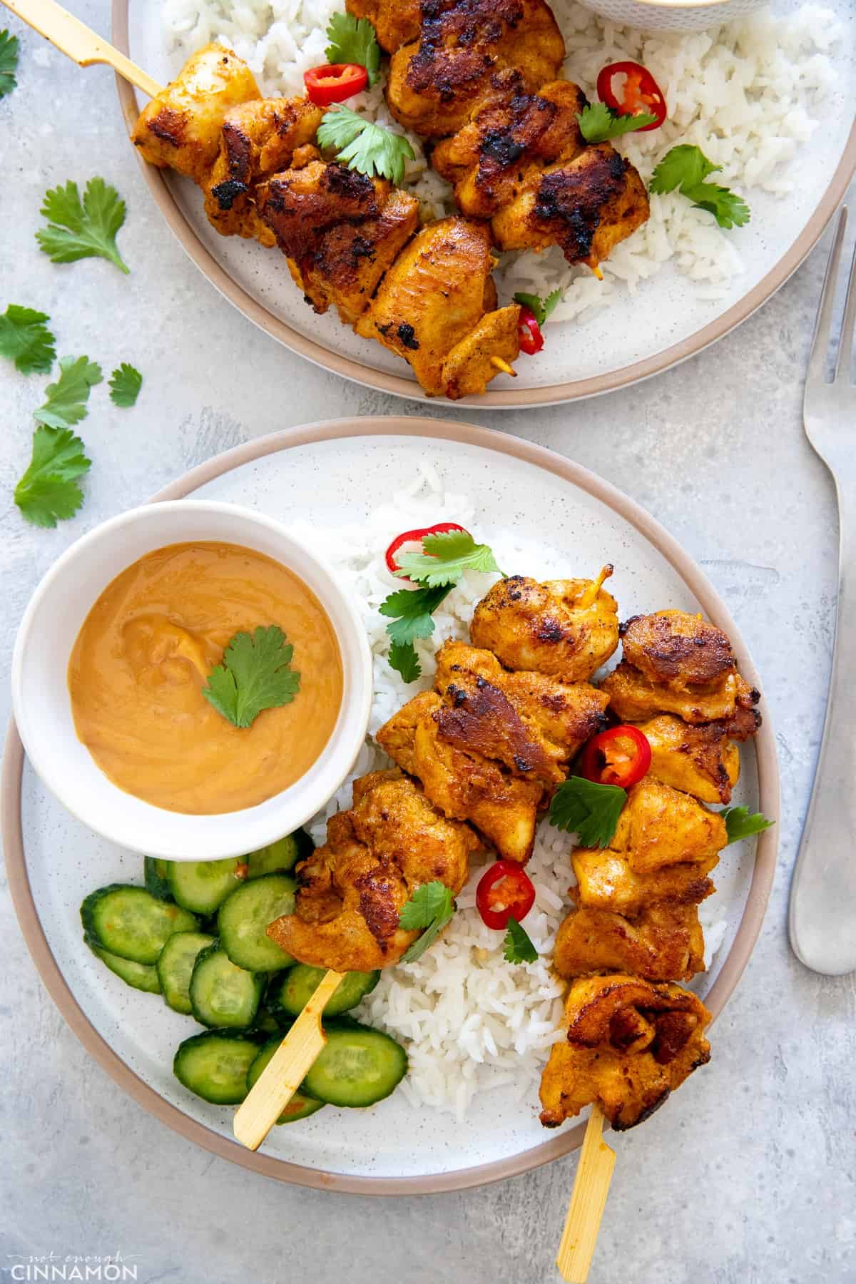 overhead shot of satay chicken skewers served with a side of peanut sauce and thai cucumber salad 