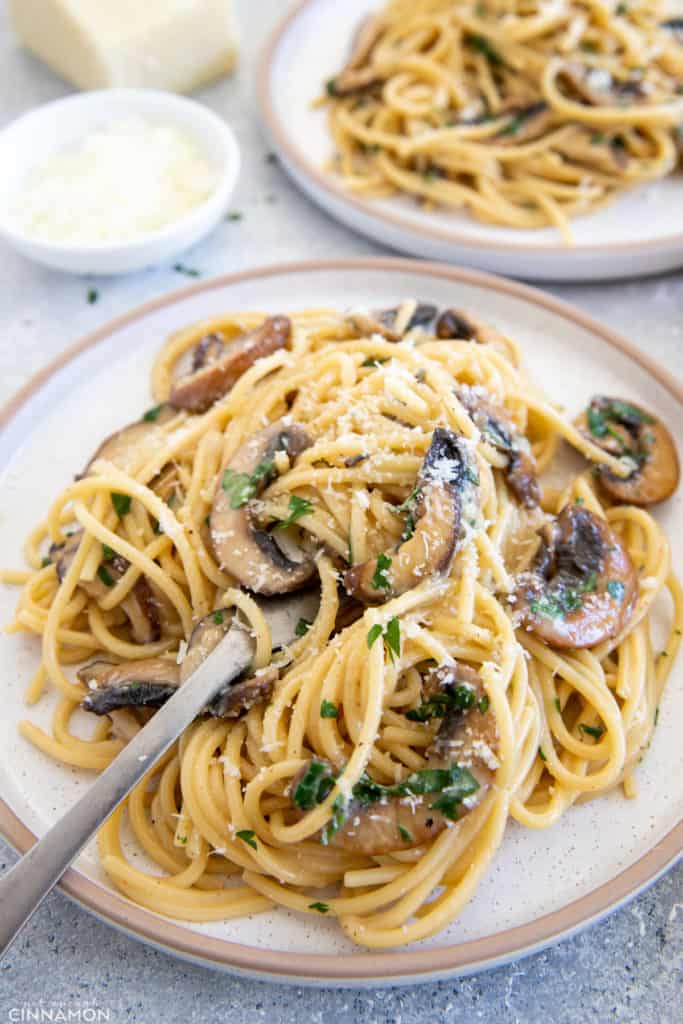 a plate of mushroom carbonara with a fork sticking in 