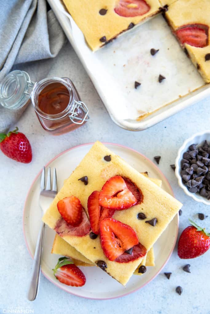 overhead shot of a stack of paleo keto sheet pan pancakes with strawberries and chocolate chips