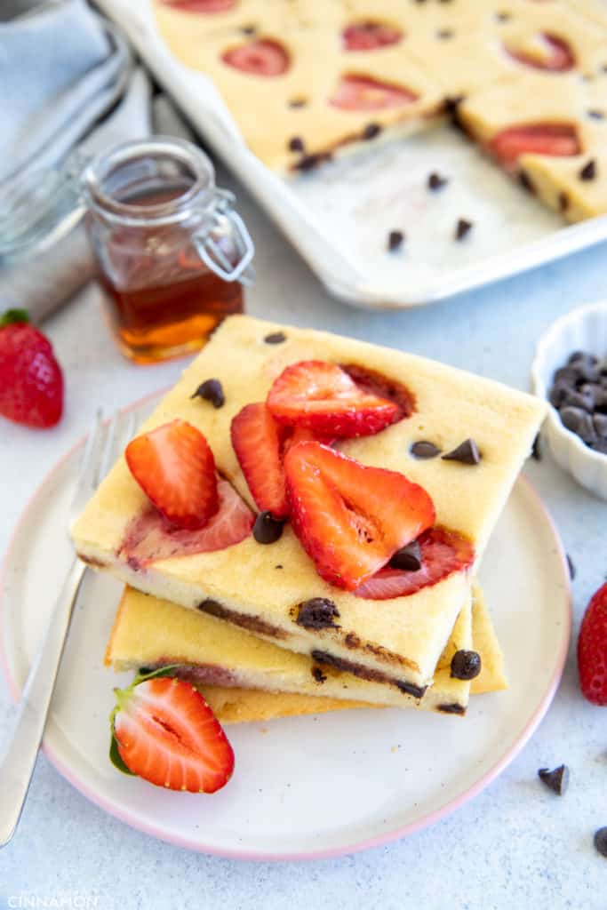 3 stacked squares of sheet pan pancakes with chocolate chips and strawberries
