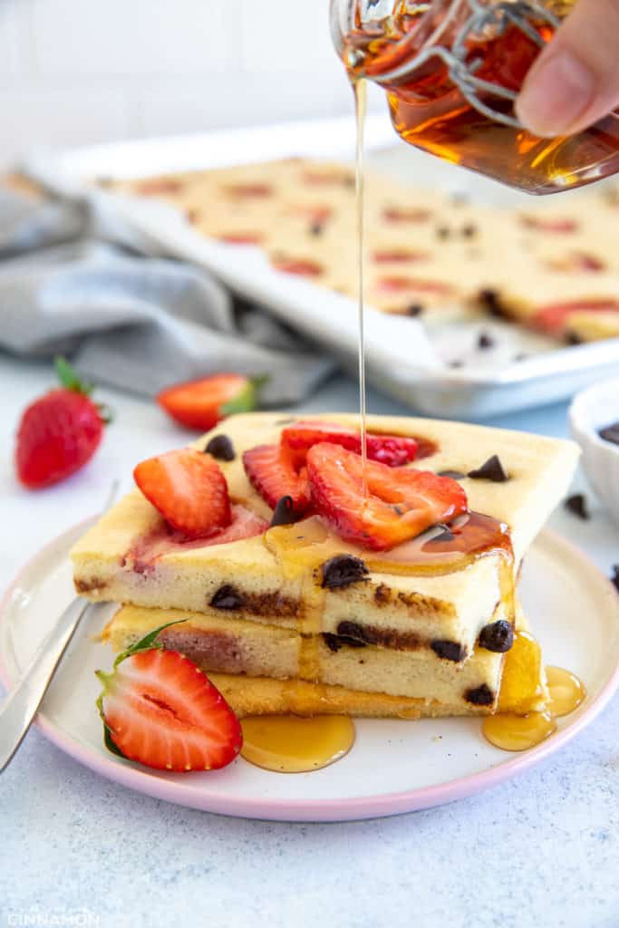 a stack of paleo keto sheet pan pancakes on a plate being drizzled with maple syrup 