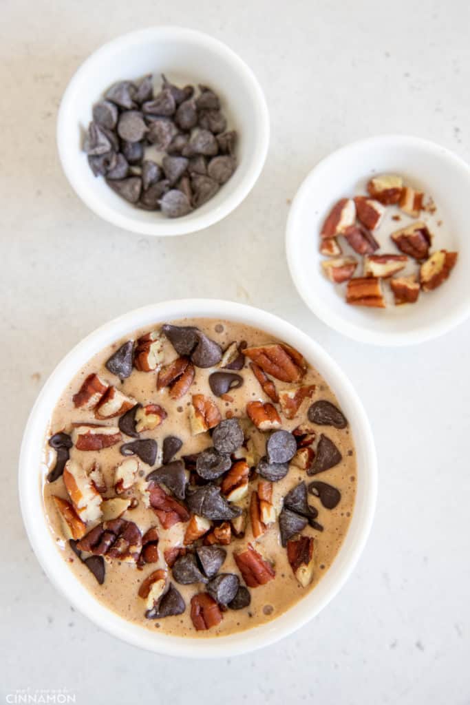 Tiktok blended baked oats batter in a small ramekin being topped with chopped pecans and chocolate chips 